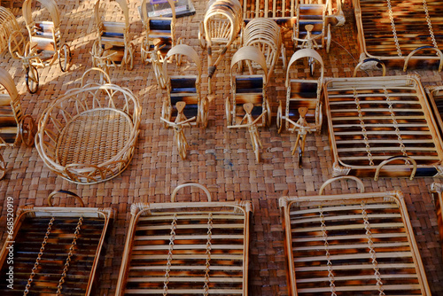 Bamboo made small toys resembling rickshaws, baskets and beds are arranged for sale  photo