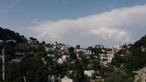 Drone shot soaring over Capri, Italy's urban housing to reveal the sea beyond the horizon. photo