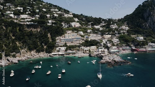 Drone shot pulling away from Capri, Italy with boats lining the water. photo