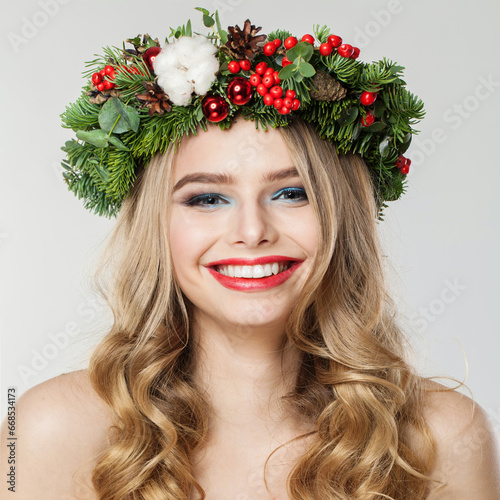 Portrait of cheerful young laughing woman with makeup, long healthy wavy hairstyle and winter decoration on white background