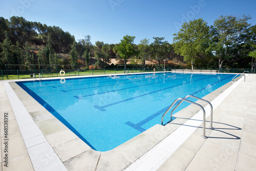 Outdoor swimming pool surrounded by trees. Recreation area. Copy space