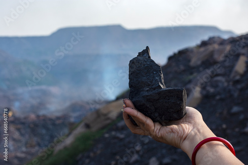 A hugh chunk of coal in the hands of a female tourist exploring a coal mine at Dhanbad, India.