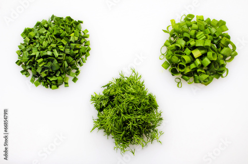 Fototapeta Naklejka Na Ścianę i Meble -  Three varieties of greens are crushed on a white background. Organic farming concept. Cooking concept. Healthy food