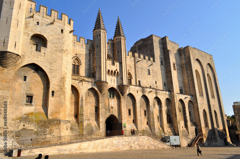 Avignon, France - Monumental building of the papal palace with the square illuminated by the setting sun.