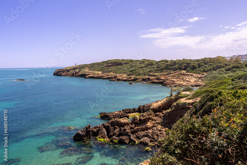 Wide angle panorama of the ruins of the Roman Archeological Park of Tipaza ( Tipasa ), Algeria. Green trees and spring maritime flowers.