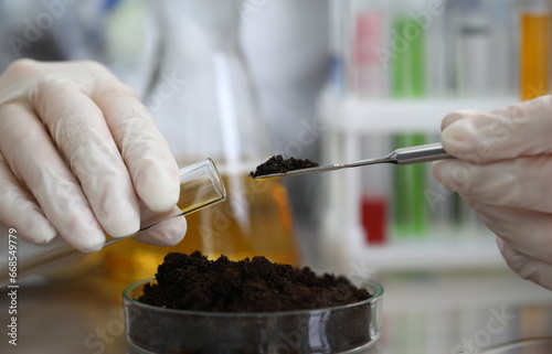 Obraz na płótnie Female chemist in white protective gloves hold test tube against chemistry lab background closeup. Express research crop soil content of beneficial and harmful substances concept w salonie