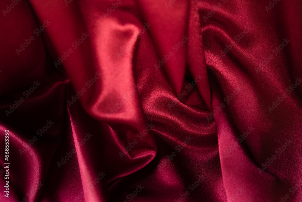 Red silk satin abstract background. Beautiful soft wavy folds on smooth luxury shiny fabric with drape. Anniversary, Christmas, wedding, valentine, celebration concept. Copy space. Element design.