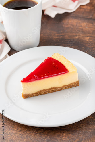 Delicious strawberry cheesecake with coffee next to it on wooden table
