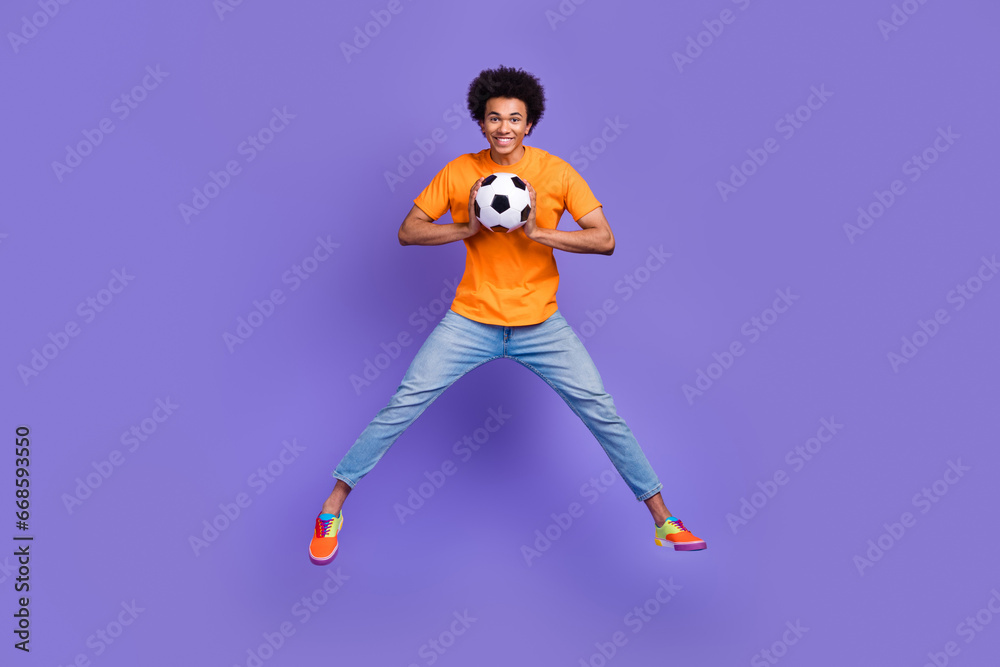 Full size body photo of jumping optimistic sportsman student junior team football player goalkeeper isolated on violet color background