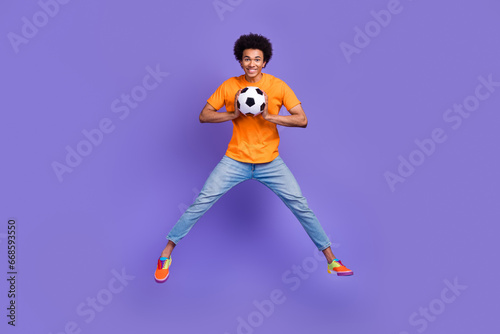 Full size body photo of jumping optimistic sportsman student junior team football player goalkeeper isolated on violet color background © deagreez