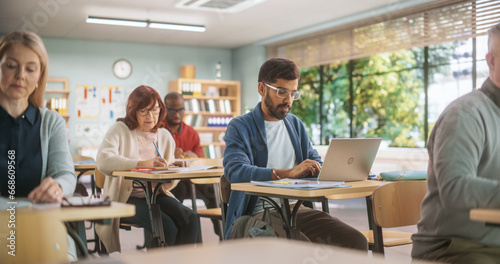 Group of International Mature Students Studying in Classroom. Modern Adult Training Center Help People to Develop New Useful Skills Throughout Life. Adults Writing in Notebooks and Using Computers