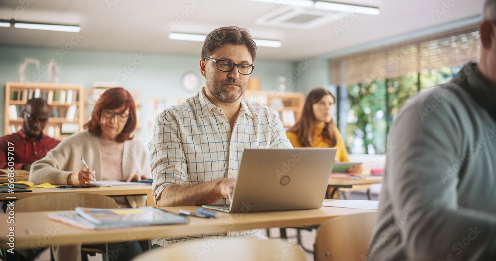 Middle-Aged Man Studying in Classroom, Using Laptop to Write Down Lecture Notes. Group of People Taking a Workshop on Improving Professional Soft Skills. Adult Education Center Concept