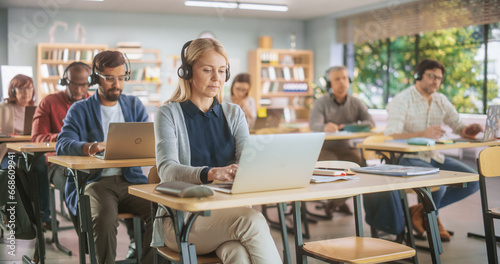 Diverse Mature Students Learning in Classroom, Sitting Behind Desks with Headphones, Using Laptops and Writing in Notebooks. Teacher Giving an Adult Education Course Remotely Online photo