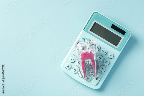 Tooth with calculator on blue background, dental cost and insurance