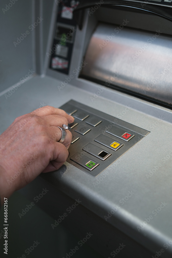 Middle-aged woman using ATM pressing the PIN security on the number pad. Middle-aged woman using ATM pressing the PIN security on the number pad.