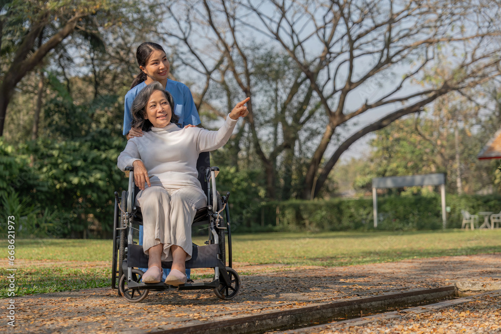 Happy nurse and elderly woman sitting in wheelchair enjoying outdoor. Beautiful nurse with senior woman in wheelchair at outdoor park. Smiling disabled old lady in wheelchair at park. Happy nurse and elderly woman sitting in wheelchair enjoying outdoor. Beautiful nurse with senior woman in wheelchair at outdoor park. Smiling disabled old lady in wheelchair at park.