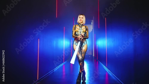Fashion model posing Fantasy cyborg woman creative robot costume metal body creative makeup, cyberpunk style blonde hair. Sexy alien girl in virtual reality war warrior future vr laser sword in hands 