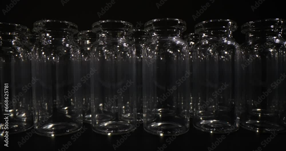 Empty glass vials in rows used for production and packaging of vaccines on black background. Medical glassware Empty glass vials in rows used for production and packaging of vaccines on black background. Medical glassware