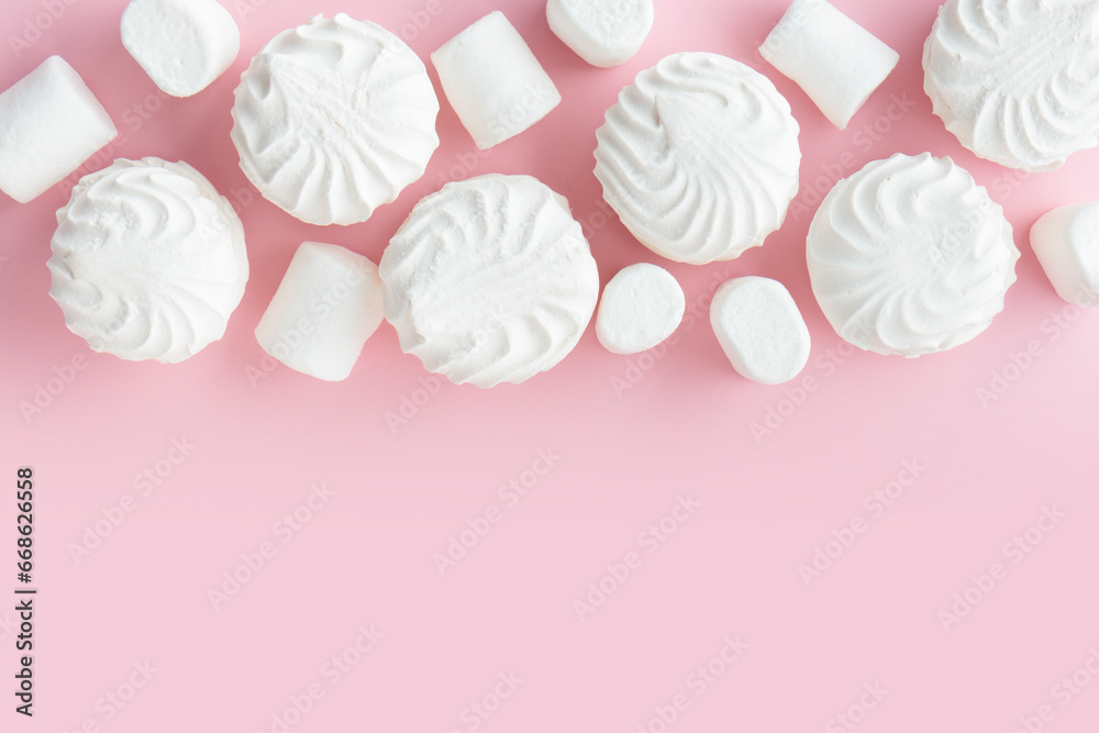 White marshmallows and zephyr on light pastel pink table. Banner with empty space for the text