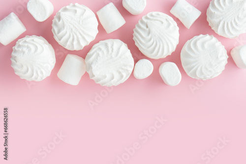White marshmallows and zephyr on light pastel pink table. Banner with empty space for the text