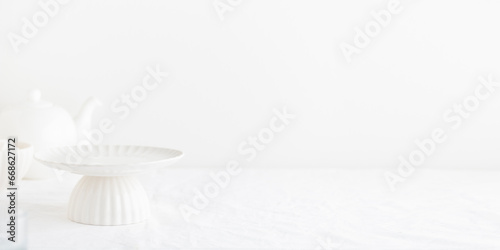 Empty tableware - white plate cakestand on white table as a background for a dessert