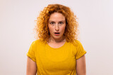 Portrait of shocked ginger woman looking at camera.