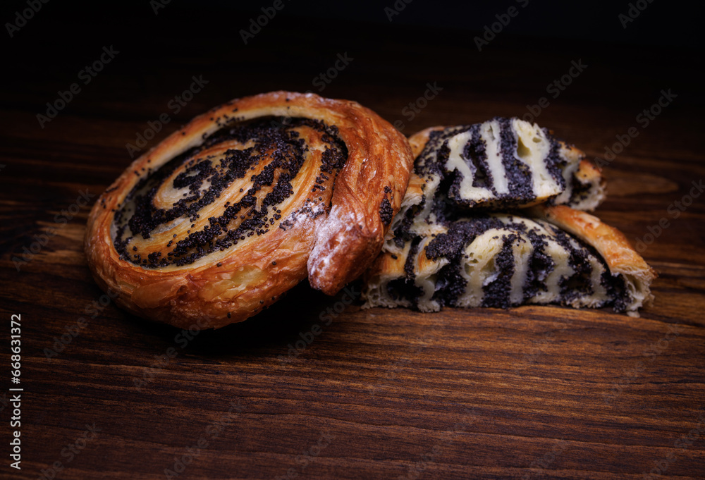 Two poppy seed buns whole and cut on a wooden background. Two poppy seed buns whole and cut on a wooden background.