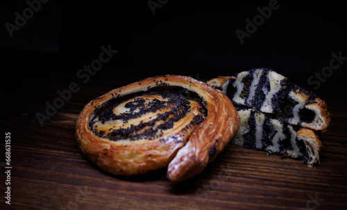 Two poppy seed buns whole and cut on a wooden background. photo