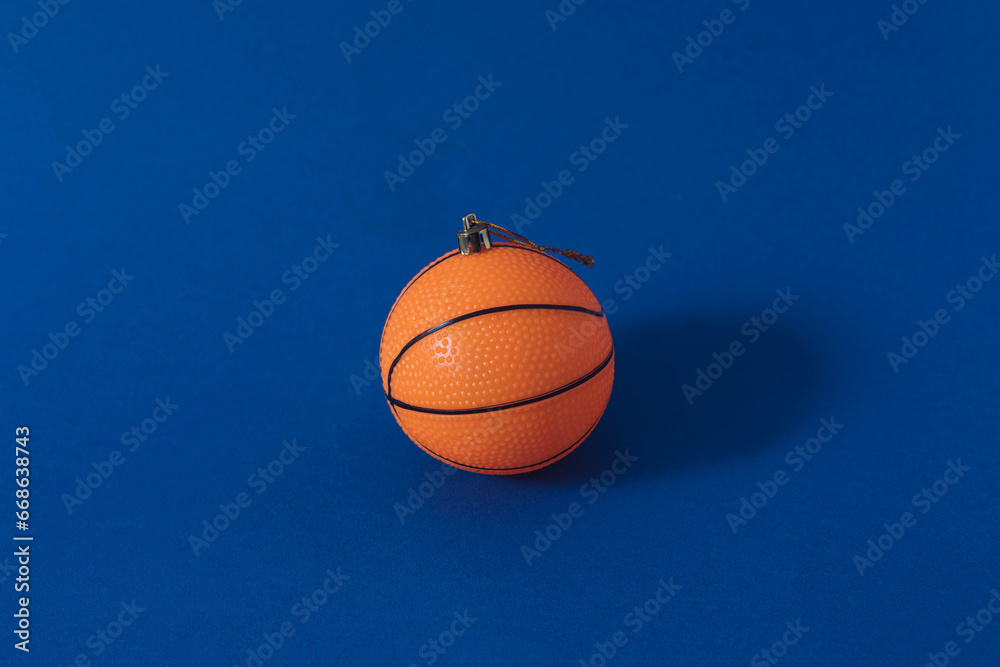 Minimal Christmas scene with orange basketball as Christmas tree bauble. Holiday and sport concept.