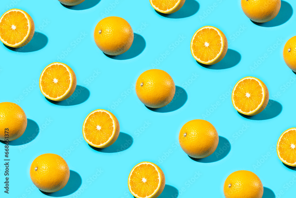 Trendy Summer food pattern made with oranges on bright light blue background. Whole and sliced oranges. Minimal summer concept.