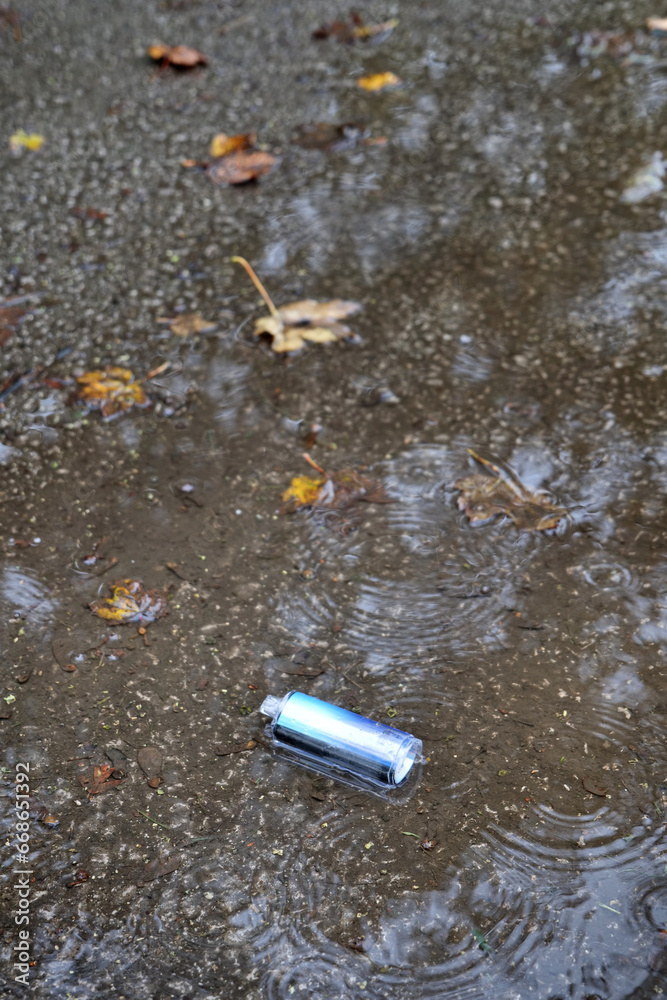 A metallic electronic cigarette vape has been left, discarded in a puddle in the rain.