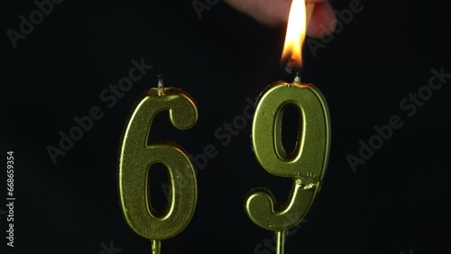 close up on the gold number sixty nine candle on a dark background.
 photo
