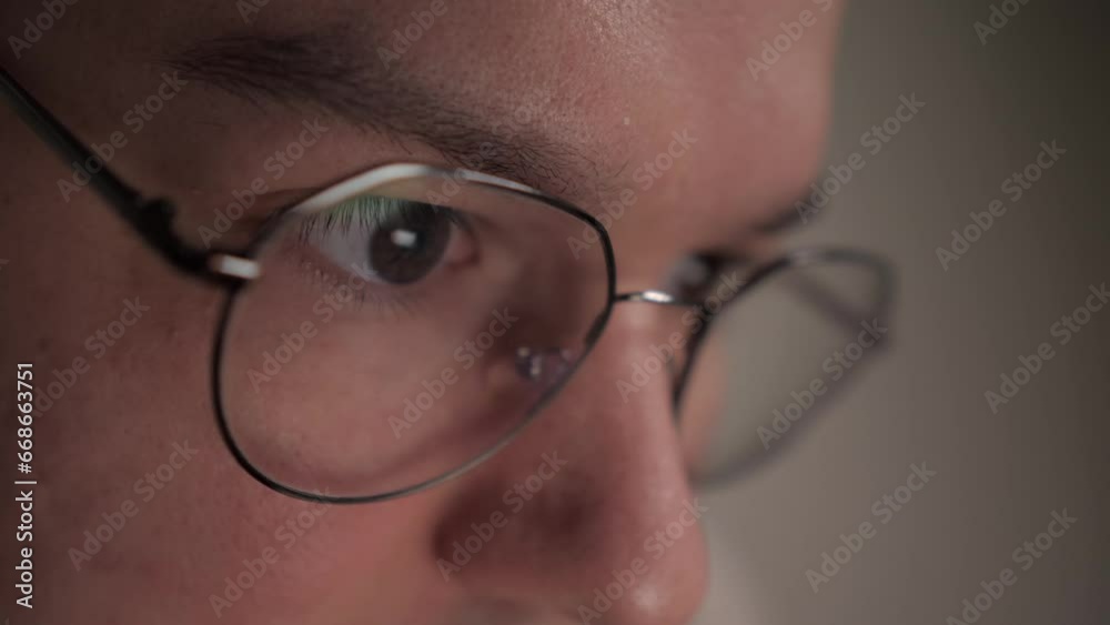 Close up view of focused man wears computer glasses for reducing eye strain. Man looking at computer screen and reading text using internet. Working online concept, digital. Close up view of focused man wears computer glasses for reducing eye strain. Man looking at computer screen and reading text using internet. Working online concept, digital.