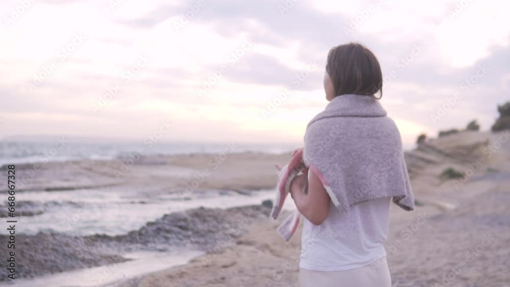 Brunette woman throwing a warm sweater on her shoulder in the evening by the sea. Brunette woman throwing a warm sweater on her shoulder in the evening by the sea.