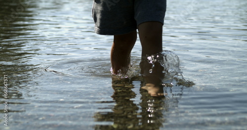 Child feet walking in lake shore water photo