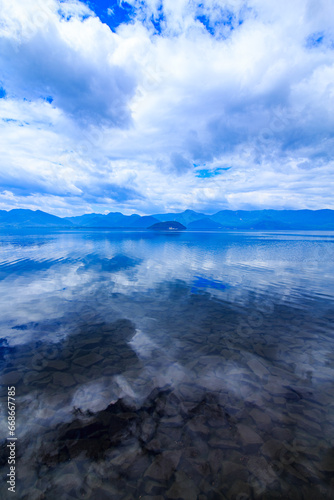 北海道、屈斜路湖の雲に覆われた空を鏡の湖面に反射する風景。