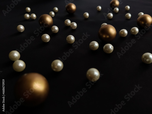 Scattered Plastic beads, white and golden on black background. Beads for jewelry making.