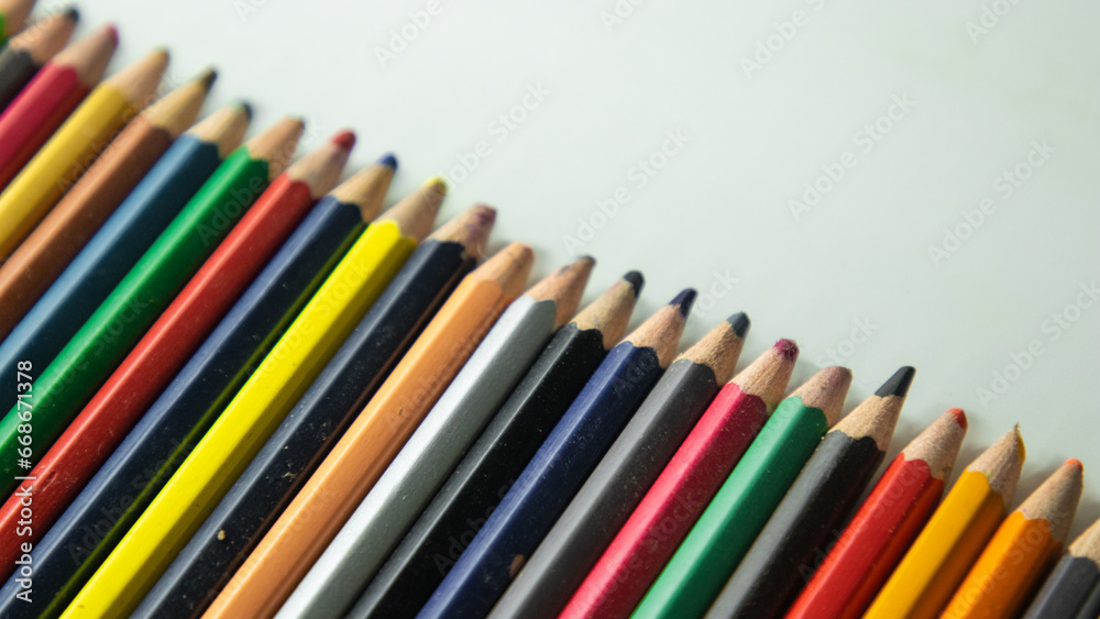 Colored pencils arranged in rows on a white background. Colored pencils arranged in rows on a white background.