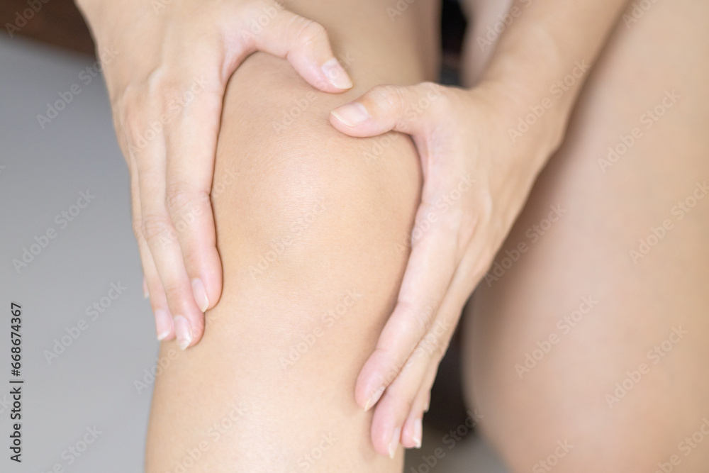 Women touching her right knee by two hands. Knee pain symptom of women. Blank space at knee for adding illustrations.