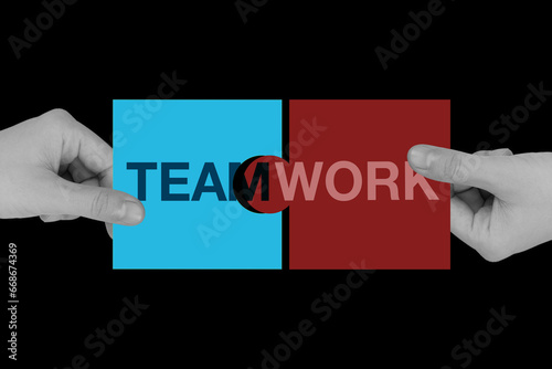 Teamwork letters jigsaw being connected by two hands to make the word completed on black background.