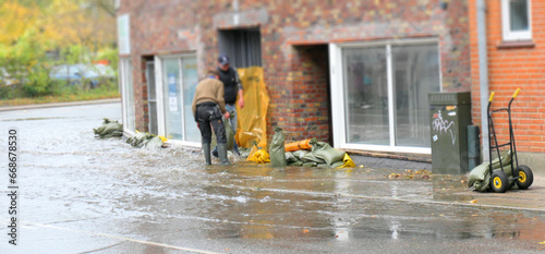 Flooded Danish city with water in the streets and people trying to protect the buildings from water damage with sandbags