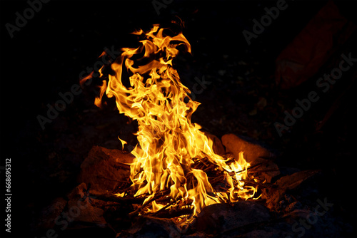 Blazing fire close-up. There is a fire burning in the forest for cooking and creating heat. The texture of burning branches. Bright flames and sparks from the fire