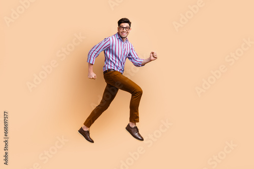 Full length photo of cheerful nice crazy man wear trendy clothes running empty space isolated on beige color background