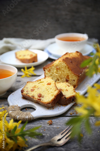 Summer dessert. Raisin cake, cups of tea and bouquet of forsythia, rustic style on wooden background