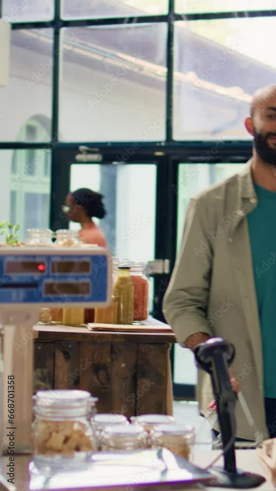 Vertical video Salesperson in eco store weighs fresh produce and groceries for middle eastern buyer by using modern scale at cash register. Retailer in local shop selling bulk pantry products. Vertical video Salesperson in eco store weighs fresh produce and groceries for middle eastern buyer by using modern scale at cash register. Retailer in local shop selling bulk pantry products.
