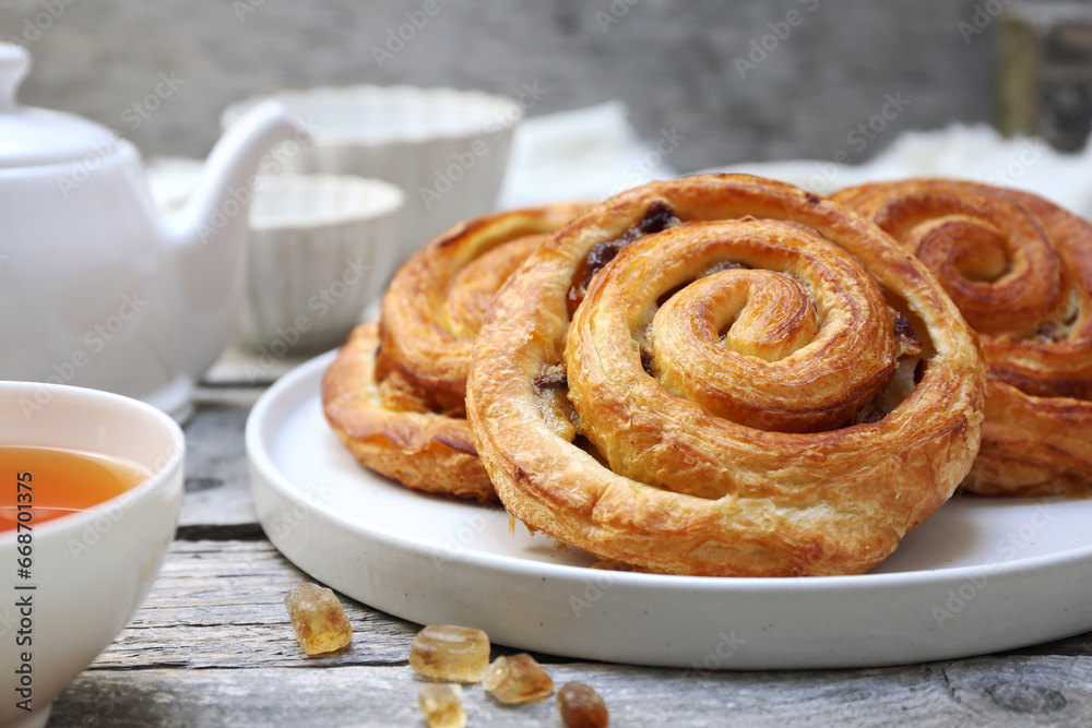French roll raisin buns, teapot and cup of tea for sweet breakfast French roll raisin buns, teapot and cup of tea for sweet breakfast