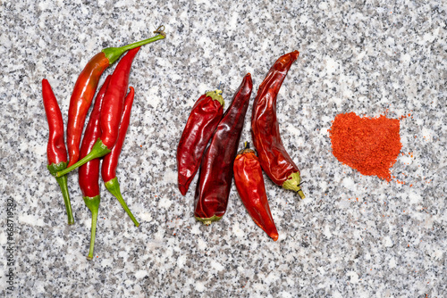 Chili pepper on granite. Transformation of hot red pepper, fresh dry and ground pepper on a granite background.