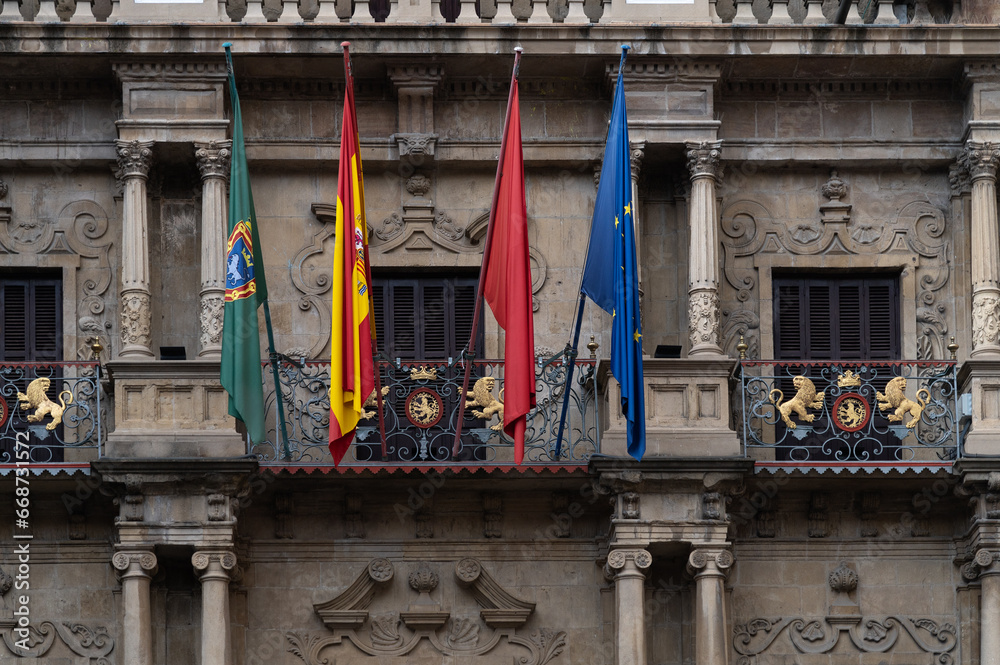 Vista del balcón del ayuntamiento de Pamplona donde se lanza el chupinazo de las fiestas de San Fermin con las banderas oficiales. - obrazy, fototapety, plakaty 