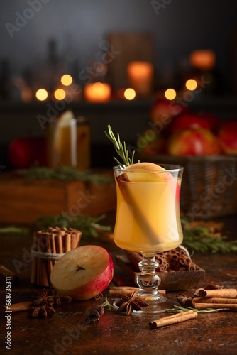 Mulled cider with apples, cinnamon, rosemary, and anise on a background of burning candles. © Igor Normann