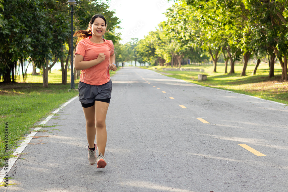 Healthy lifestyle and weight loss Concept, Active Asian Woman Jogging Outdoors in Park, Overweight Young Adult Running in Sportswear, Determined Chubby Girl Training to Lose Weight Outdoors.